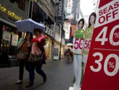 Dos mujeres surcoreanas pasan junto a un cartel que anuncia rebajas en una tienda de Seúl, Corea del Sur.