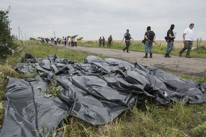 Unos bolsas tapan los cadáveres de varios pasajeros del vuelo de Malaysia Airlines al borde de una carretera en la que activistas prorrusos, algunos encapuchados, controlan la situación.