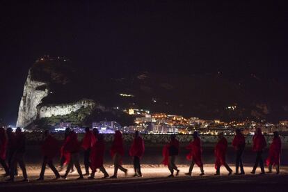 Inmigrantes subsaharianos caminan hacia el Centro de Atención Temporal de Extranjeros desde el muelle situado en Crinavis (Algeciras, Cádiz). Al fondo, el Peñón de Gibraltar, el 15 de agosto de 2018, en una jornada en la que se rescataron a 524 migrantes en el mar de Albóran y en aguas del Estrecho.