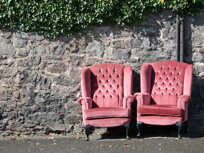 Pink velvet armchairs nestled together outside against stone wall