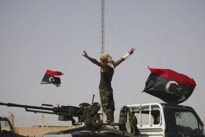 Un miliciano rebelde hace el signo de la victoria, junto a unas banderas monárquicas, en un control de carretera cercano a Bani Walid.