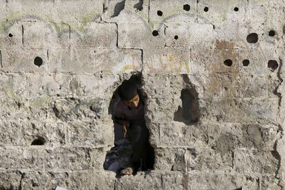 Destrucción en las calles de Gaza tras los bombardeos que ha llevado a cabo la aviación israelí, según residentes locales. En la imagen, un palestino se asoma por el agujero de una pared cerca de un campo de entrenamiento de Hamas.