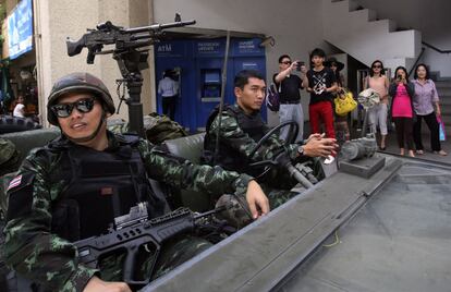 Los viandantes hacen fotos a los soldados que patrullan por las calles de Bangkok.