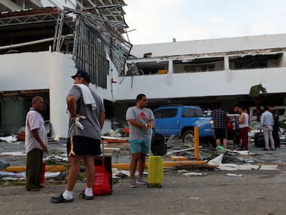 Un grupo de personas espera junto un edificio destruido por el paso del huracán 'Otis', en Acapulco, este 26 de octubre.