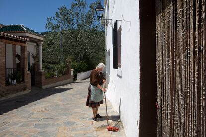 Adela, vecina de Macharaviaya (Málaga), friega la puerta de su casa.