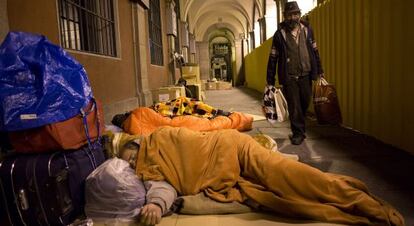 Un hombre pasa junto a las personas que duermen en la plaza Mayor.