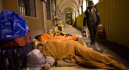 Un hombre pasa junto a las personas que duermen en la plaza Mayor.