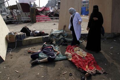 Dos mujereshablan con uno de los heridos tendidos en el suelo después de una represión policial egipcia en el ampamento de protesta por los partidarios del depuesto presidente Mohamed Morsi y los miembros de la Hermandad Musulmana.
