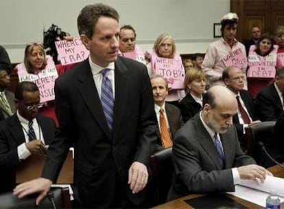 Bernanke (sentado) y Geither a su llegada a su comparecencia ante el Comité de Actividades Financieras del Congreso de EE UU, con un grupo de ciudados protestando detrás de ellos