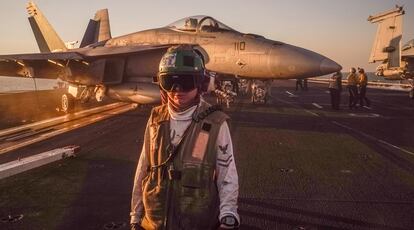 Suboficial del servicio de señales de aterrizaje del USS Truman, en la cubierta de vuelo ante un F-18. Viste la camisa blanca que distingue sus actividades.

