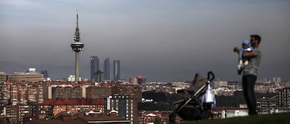 Un hombre con su beb&eacute; pasea por el barrio de Entrev&iacute;as, en Madrid.