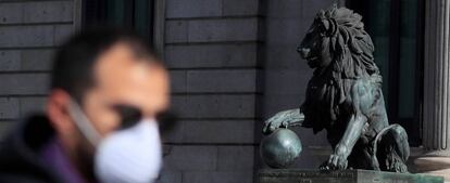 Un hombre con mascarilla pasa frente al Congreso de los Diputados.