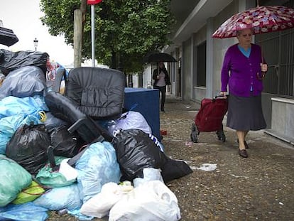 Una mujer pasa junto a las basuras acumuladas por la huelga en Jerez.