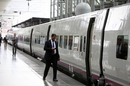 Un pasajero mira el móvil antes de entrar en un tren AVE