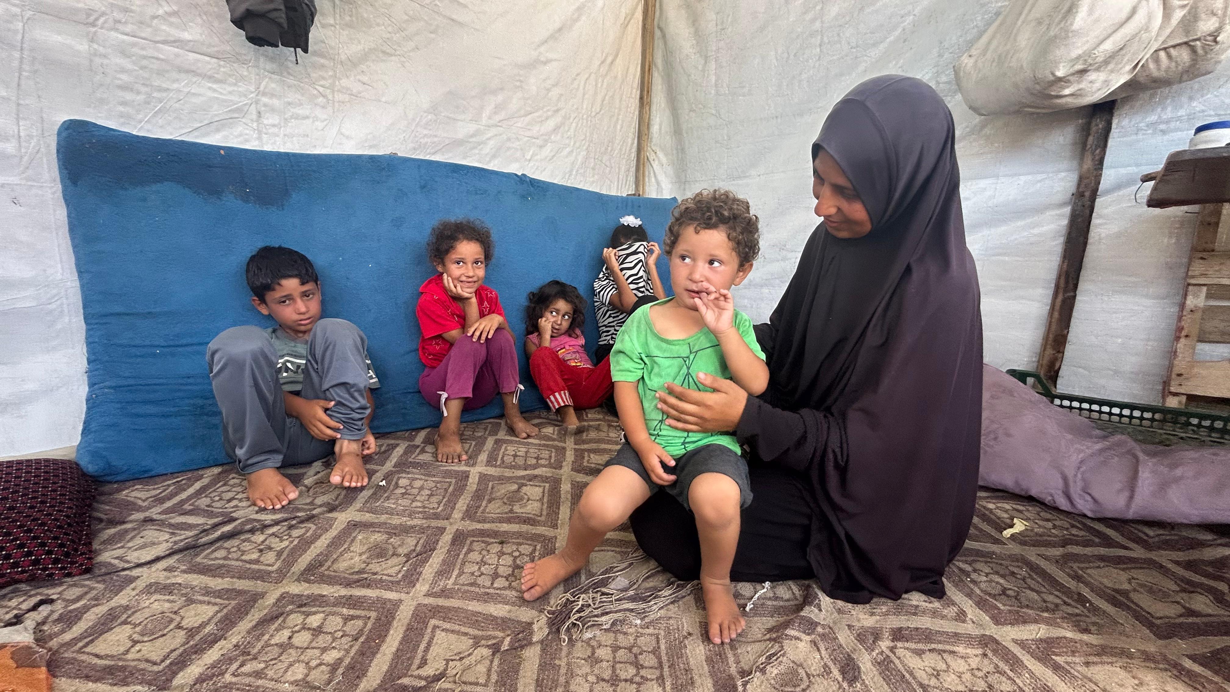 Wafa Mohammed, junto a sus hijos en la tienda en la que viven en el campamento de Al Mawasi, en Gaza.