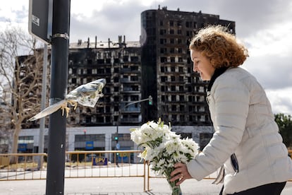 A woman leaves a bouquet of flowers on Saturday in memory of the victims of the fire in a building in the Campanar neighborhood of Valencia that claimed the lives of at least 10 people. 