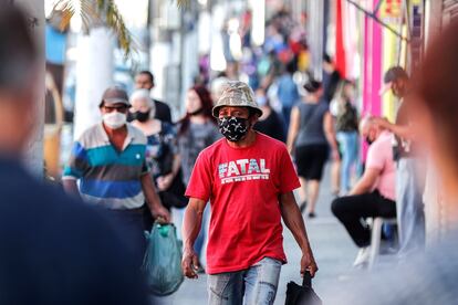 Pessoas com máscaras em frente a lojas fechadas devido à quarentena em São Paulo.