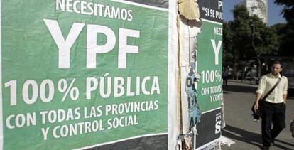 Un hombre pasa frente a varios carteles en los que se pide la estatización de YPF.