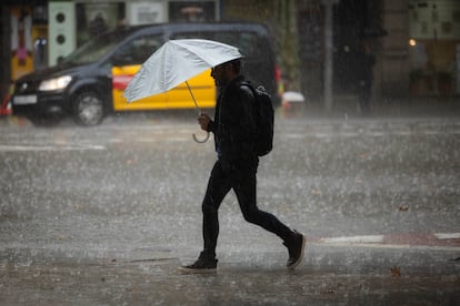 Un viandante se protege de la lluvia en la avenida del Paral·lel de Barcelona, este lunes.