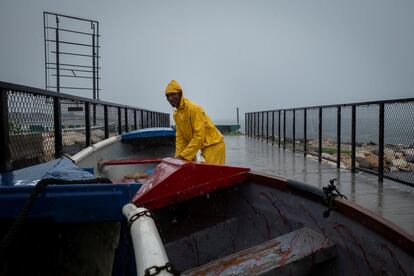 Un pescador asegura botes pesqueros en Kingston, al acercarse el huracán, este miércoles.