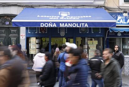 Varias personas pasan delante de la administración de lotería de Doña Manolita, en el centro de la capital, una de las más solicitadas en estas fechas. La cola para hacerse con un décimo dura varias horas.