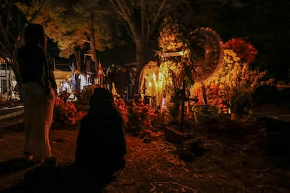 Habitantes de San Jerónimo Purenchécuaro (Michoacán), uno de los poblados a las orillas del río Pátzcuaro, colocan flores de cempasúchil en las tumbas de los difuntos.