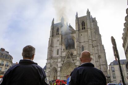 Agentes de la policía francesa contemplan los trabajos de extinción del incendio en la catedral de Nantes.