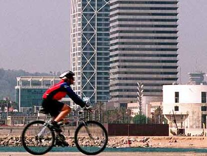 Un ciclista pasea ante la torre Mapfre en la Villa Olímpica Barcelona.