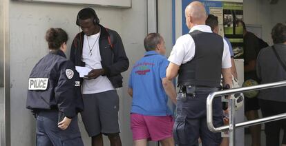 Two French police officers intercept a migrant at the border.