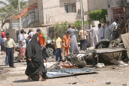 Unos grupo de niños iraquíes miran los restos de un coche bomba en el distrito de Ressala, en Bagdad.