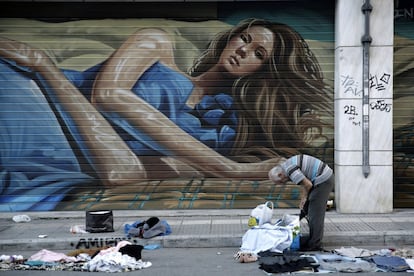 Un vendedor ambulante recoge su ropa en las afueras de una tienda en el centro de Atenas, Grecia.