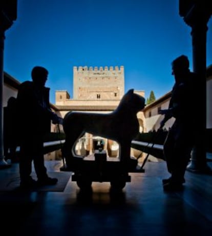 Dos operarios trasladan por el patio de Comares, al fondo la torre, uno de los leones restaurados en 2007.