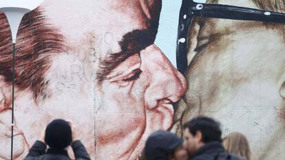 Una persona toma fotos a una pintura que representa el ex líder soviético Leonid Brezhnev besando a su homólogo alemán oriental Erich Honecker.