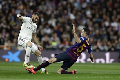 El centrocampista del F.C. Barcelona, Sergio Busquets, realiza una entrada sobre el delanter francés del Real Madrid Karim Benzema.