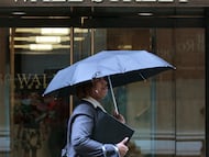 Una mujer camina con un paraguas por Wall Street en Nueva York.