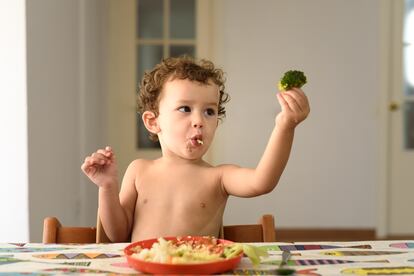 Un niño juega con un brócoli.