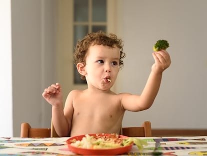 Un niño juega con un brócoli.