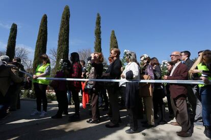 Un grupo de gente espera en fila para dejar flores en el monumento a las víctimas en el Parque del Retiro.