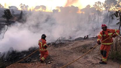 Los bomberos sofocan las llamas en el incendio de este domingo en el asentamiento chabolista de San Jorge, en Palos de la Frontera (Huelva).