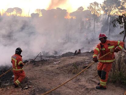 Los bomberos sofocan las llamas en el incendio de este domingo en el asentamiento chabolista de San Jorge, en Palos de la Frontera (Huelva).