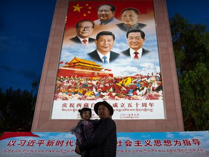 Un hombre posa con una niña frente a un mural que representa al presidente Xi Jinping y otros líderes chinos en la plaza del palacio de Potala, en Lhasa, el 1 pasado de junio