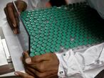 FILE PHOTO: An employee in personal protective equipment (PPE) removes vials of AstraZeneca's COVISHIELD, coronavirus disease (COVID-19) vaccine from a visual inspection machine inside a lab at Serum Institute of India, in Pune, India, November 30, 2020. REUTERS/Francis Mascarenhas/File Photo