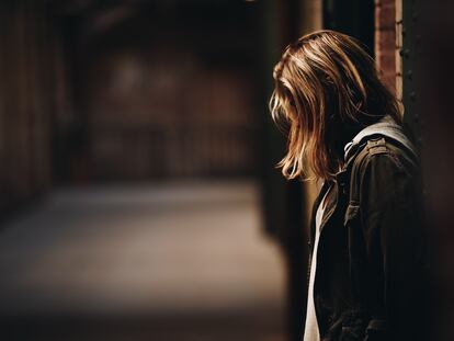 Una chica triste está sola en una calle.