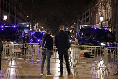 Dos jóvenes contemplan varias furgonetas de los Mossos de Esquadra antes de la llegada de los Reyes en el Liceu.