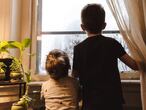 Dos niños miran por la ventana.