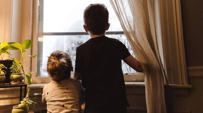 Dos niños miran por la ventana.  
