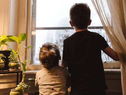 Dos niños miran por la ventana.  