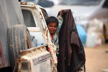 A displaced Syrian child, who fled the countryside surrounding the Islamic State (IS) group stronghold of Raqa, looks on from the door of a car at a temporary camp in the village of Ain Issa on April 28, 2017. / AFP PHOTO / DELIL SOULEIMAN