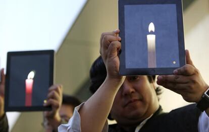 El analista tecnológico Steve Nagata (dcha.) sostiene un iPad con la imagen de una vela, durante una vigilia frente a la tienda de Apple en Tokio