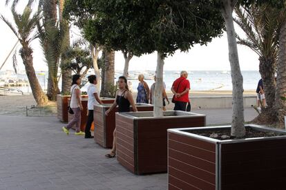 Varios viandantes pasan entre los maceteros instalados en el paseo marítimo de Santiago de la Ribera (Murcia).